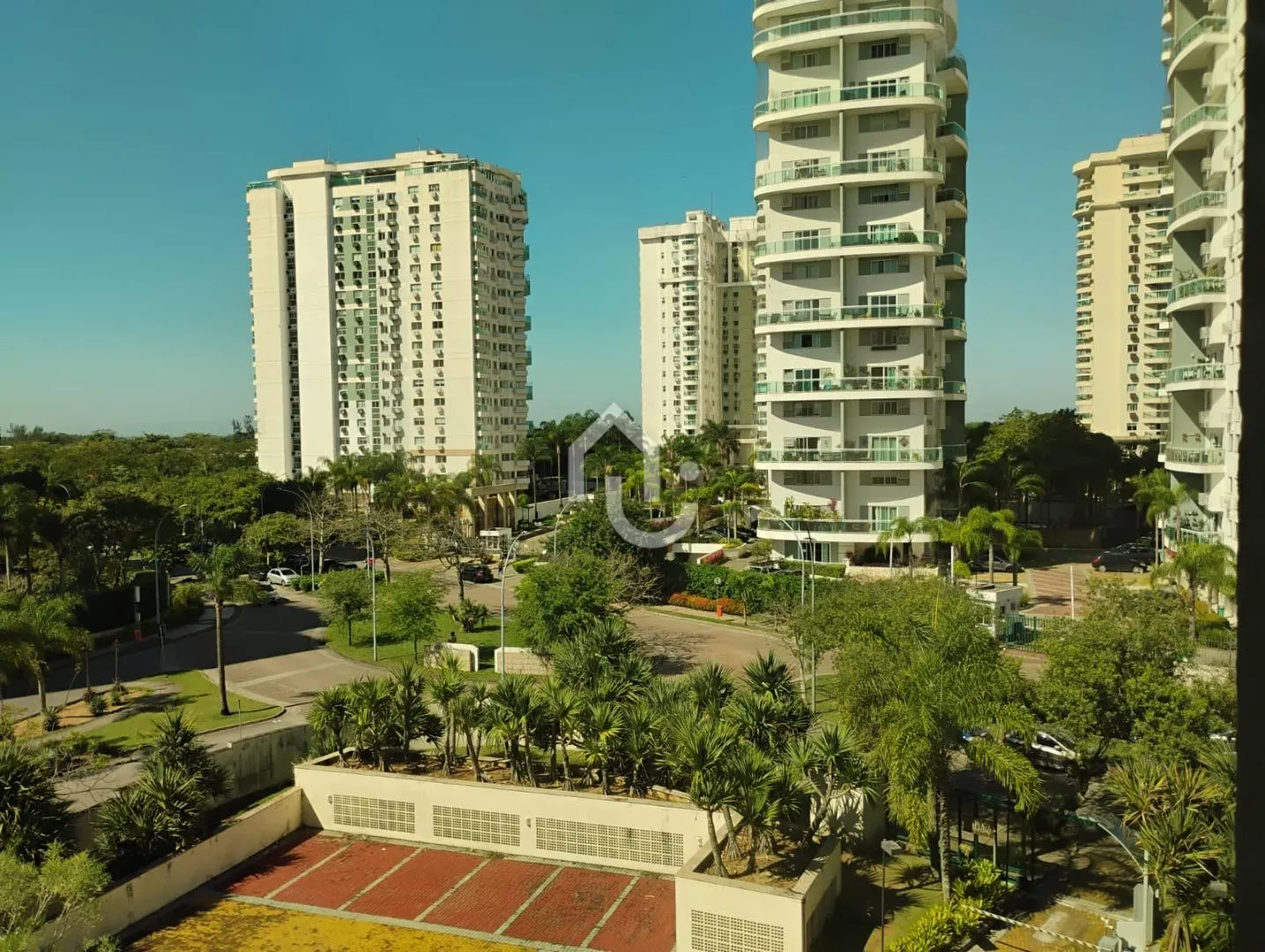 Vista de apartamento na Barra da Tijuca para condomínio arborizado com torres residenciais ao fundo.